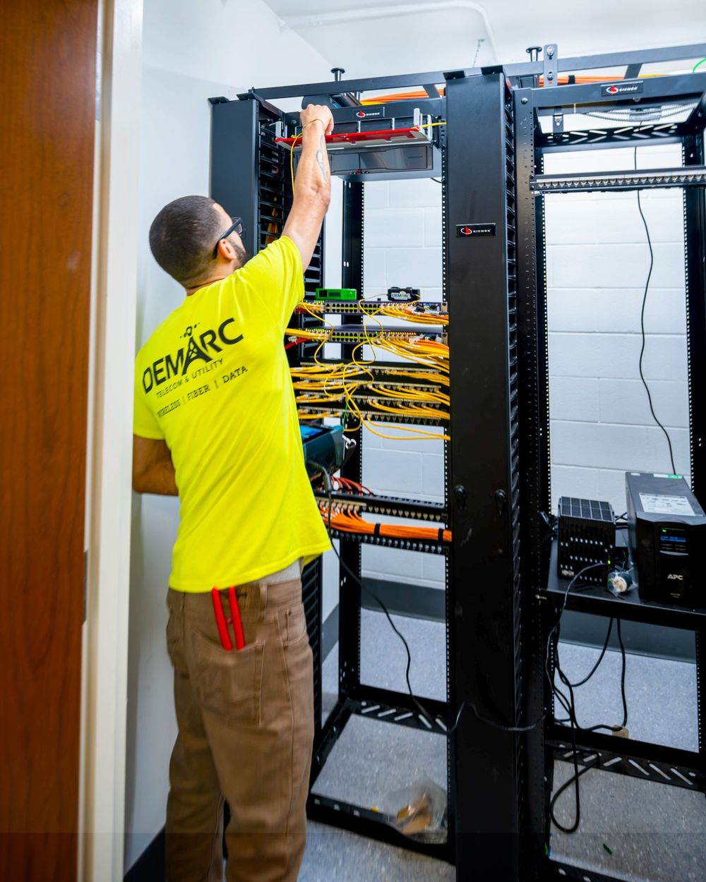 Demarc technician working in a telecom room with Siemon racks